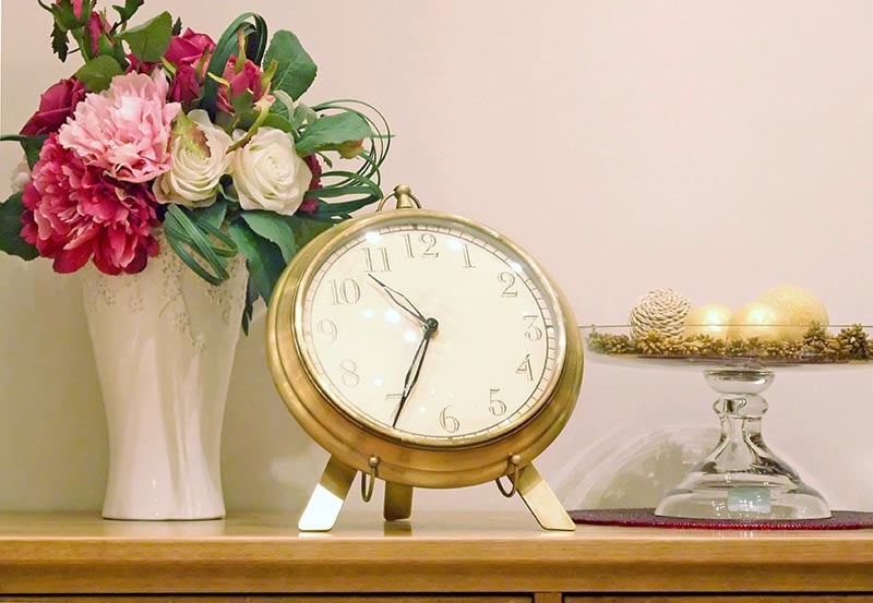 An elegant tabletop arrangement featuring a vintage-style clock.